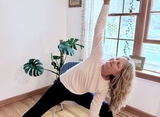Serrina Davis in an extended side angle pose, supported by a chair and yoga block