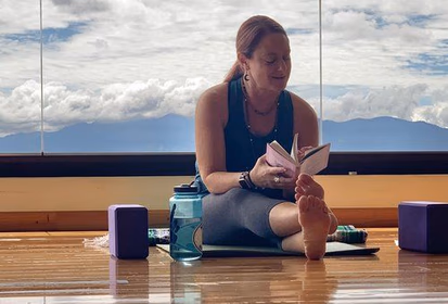 A Branches of Yoga teacher sitting down and reading a book.