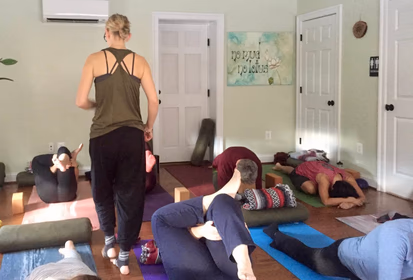 Yoga teacher walking amongst students lying on their back.